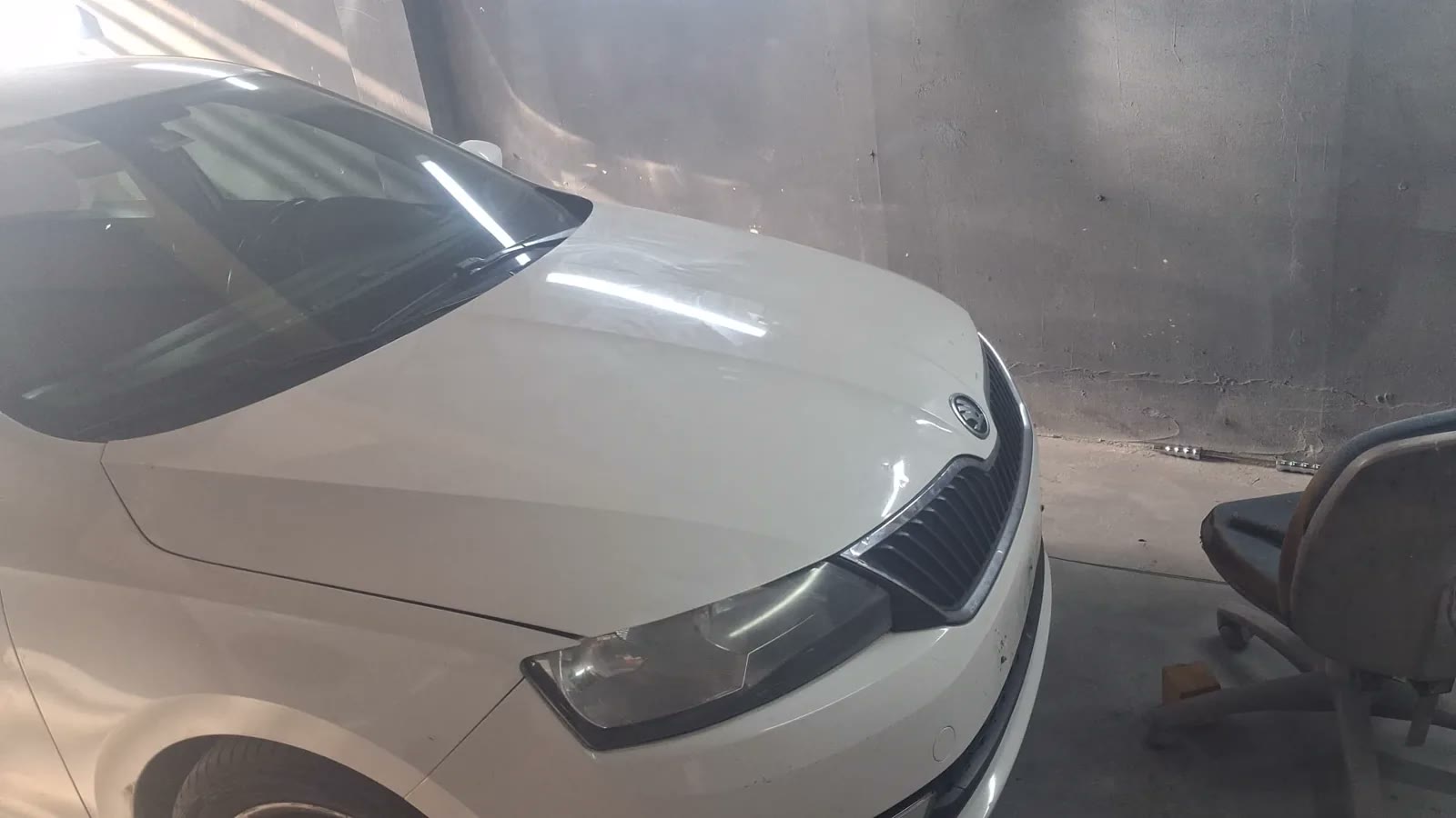 Beyaz Škoda aracın tamamlanan kaputunun sağ ön açıdan görünümü